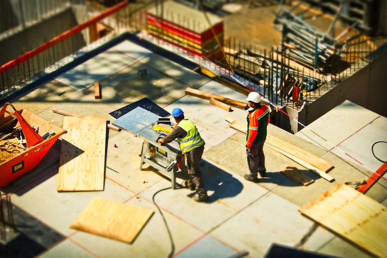 Services Construction workers engaging in tasks at an outdoor building site with safety hats and equipment.