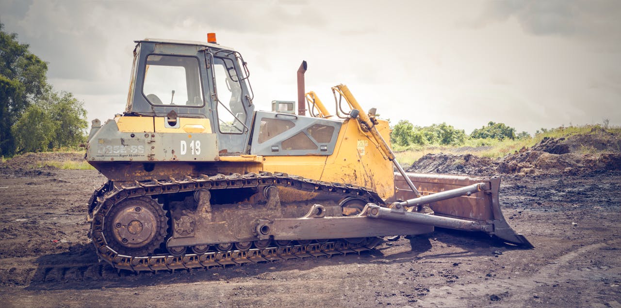 Services A powerful bulldozer on muddy construction ground under a cloudy sky.