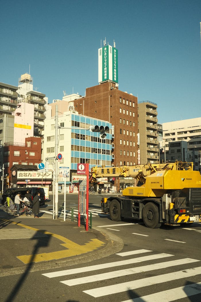 A vibrant city street scene featuring buildings, vehicles, and people, captured under a clear blue sky.